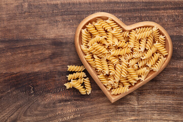 Pasta in a heart shaped wood bowl.