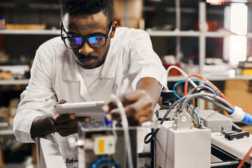 African engineer programming equipment with tablet at factory