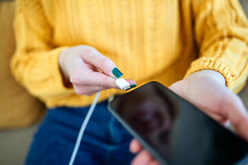 Woman hands plugging a charger in a smart phone. Woman using smartphone with powerbank, charging...