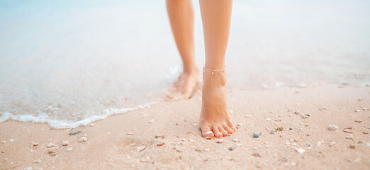 Female legs walking along the seaside barefoot, close-up of the perfect tanned legs of a girl coming out of the water after swimming. Woman relaxing on vacation, enjoying time at the beach, summer © Daria Lukoiko