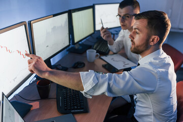 Showing graph place. Two stock traders working in the office with exchange technology