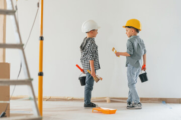 Cheerful kids. Two boys painting walls in the domestic room