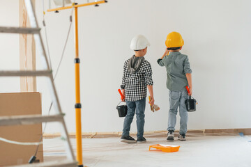 Cheerful kids. Two boys painting walls in the domestic room