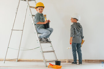 Rear view. Two boys painting walls in the domestic room