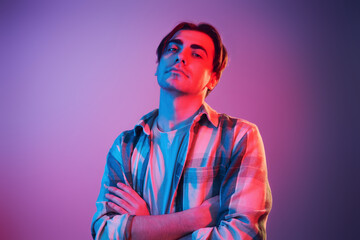 Arms crossed. Man standing in the studio with neon light