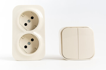 double socket and two-key light switch on white background. mechanical device for switching lighting circuit and two sockets connected by one monolithic case. shop of electronic devices for the home.