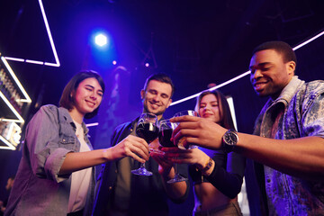 People doing cheers. Group of friends having fun in the night club together