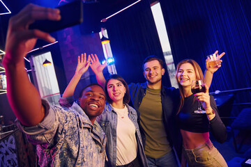 Making selfie. Group of friends having fun in the night club together