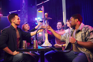 Smoking hookah. Group of friends having fun in the night club together