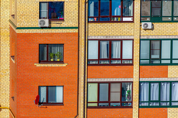 Close-up of the orange facade of an apartment building. Brick wall of the house with windows.