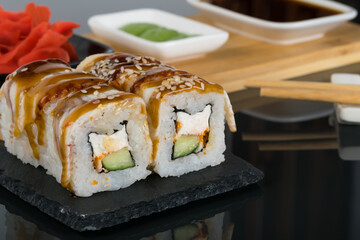 a set of rolls with eel and sauces for them on a black table