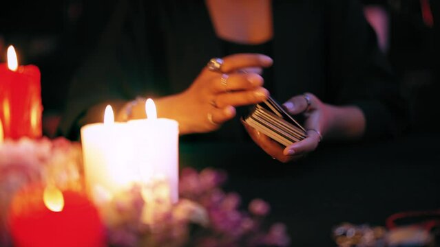 Hands of fortuneteller shuffling tarot cards in mysterious atmosphere, ritual