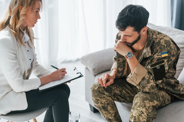 With notepad. Soldier have therapy session with psychologist indoors