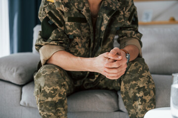 Close up view. Soldier in uniform is indoors in the domestic room