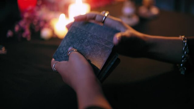 Witch shuffling tarot cards in mysterious atmosphere, fortunetelling ritual