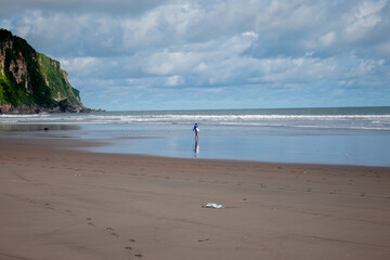 a fisherman walks along the beach with a dog