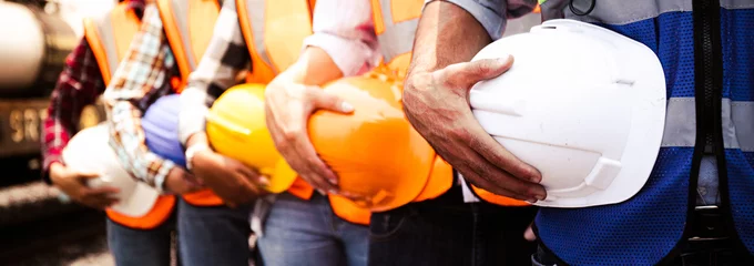 Fotobehang Engineer team holding hardhat standing in row ready for work.Worker diversity group wearing vest,ppe for safety in site train garage.Expert construction project manager leadership.banner cover design. © Chalermphon