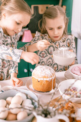 happy family candid little kids sisters girls together have fun ready springtime Easter holiday at home in kitchen decorating table and Easter cakes bakery sweet icing and candy for lunch or dinner