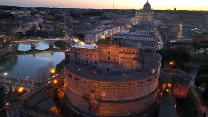 flying above Castel Sant'Angelo and San Pietro in Rome at night. Panoramic aerial view of the Tiber river, its bridges and St. Peter's, Vatican City. Center city of Roma, Italy in the evening