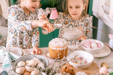 happy family candid little kids sisters girls together have fun ready springtime Easter holiday at home in kitchen decorating table and Easter cakes bakery sweet icing and candy for lunch or dinner