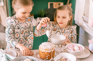 Obraz na płótnie Canvas happy family candid little kids sisters girls together have fun ready springtime Easter holiday at home in kitchen decorating table and Easter cakes bakery sweet icing and candy for lunch or dinner