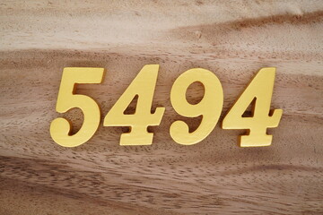 Golden Arabic numerals on a real brown and white wooden floor number 5494