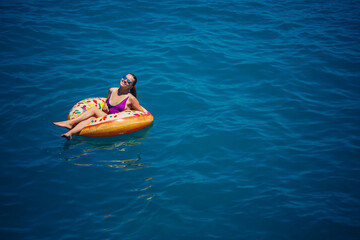 Carefree young woman enjoying a relaxing day at sea, floating on an inflatable ring. Sea vacation concept