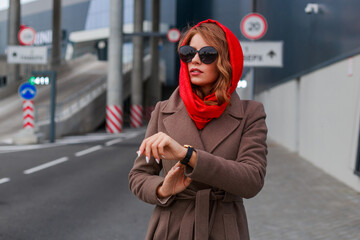 A beautiful lady in a trendy look walks in the city, a business center, a red scarf