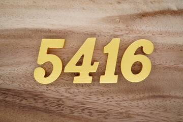 Golden Arabic numerals on a real brown and white wooden floor number 5416