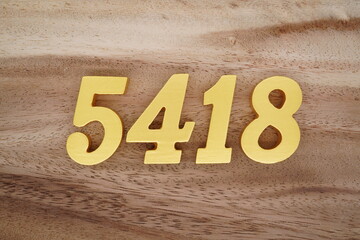 Golden Arabic numerals on a real brown and white wooden floor number 5418