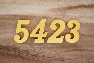 Golden Arabic numerals on a real brown and white wooden floor number 5423