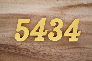 Golden Arabic numerals on a real brown and white wooden floor number 5434