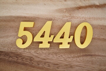 Golden Arabic numerals on a real brown and white wooden floor number 5440