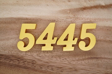 Golden Arabic numerals on a real brown and white wooden floor number 5445