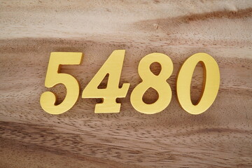 Golden Arabic numerals on a real brown and white wooden floor number 5480