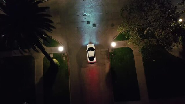 Aerial Ascending Top Down View Of White Car Stopped By The Stop Sign And Waiting At The Intersection. Night