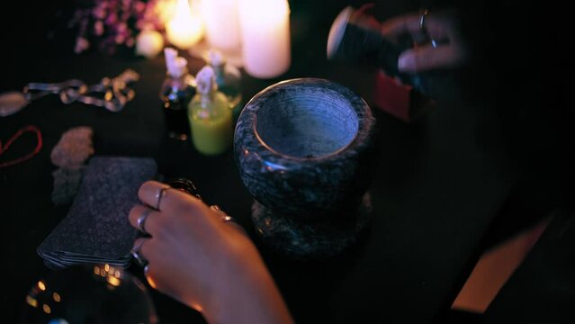 Hands of witch cooking magic potion, pounding ingredients in mortar, healing