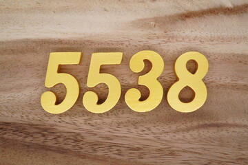 Golden Arabic numerals on a real brown and white wooden floor number 5538