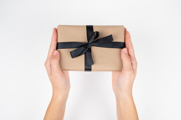 Cropped view of woman holding gift box with black ribbon isolated on white