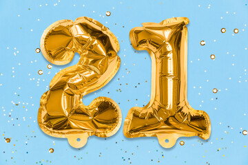 The number of the balloon made of golden foil, the number twenty-one on a blue background with...
