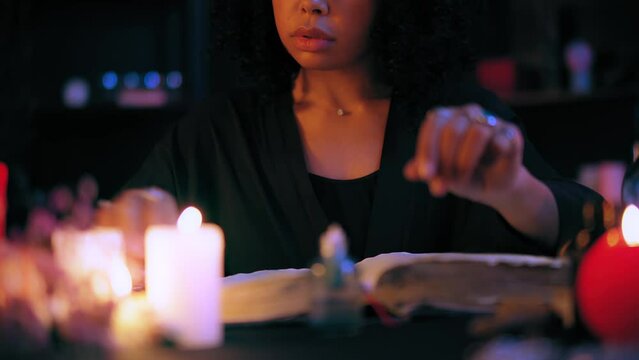 Mysterious witch preparing ingredients for magic potion, reading spell book