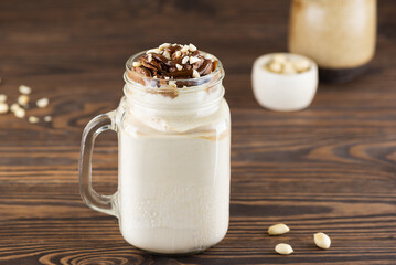 Milkshake with nuts and caramel in a mug on a wooden table. Vegan, sugar and lactose free.