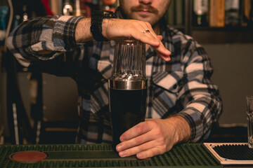 Professional bartender making cocktail for guests in shaker