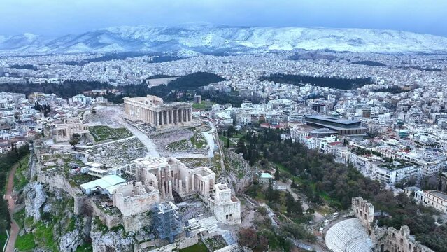 Flying around the Acropolis of Athens in the snow, aerial view of famous Greek tourist destination in winter, tourism in Greece concept