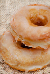 Two plain glazed doughnuts on rustic surface with copy space