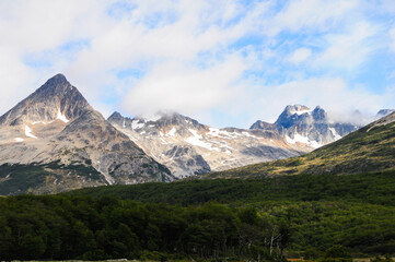 Fototapeta premium Mountain peaks covered with snow and hills with grass and vegetation