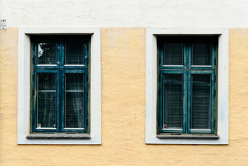 Fototapeta na wymiar Two old wooden windows painted in green on stucco facade