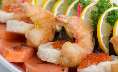 Seafood appetizers. Sandwiches with a game, a tartlet appetizer with sauce and red caviar, sliced red salmon fish and cream sauce with scrambled eggs.