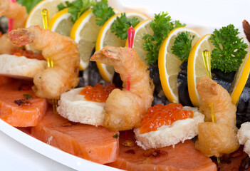 Seafood appetizers. Sandwiches with a game, a tartlet appetizer with sauce and red caviar, sliced red salmon fish and cream sauce with scrambled eggs.