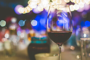red wine in glass of night party wih bokeh light.